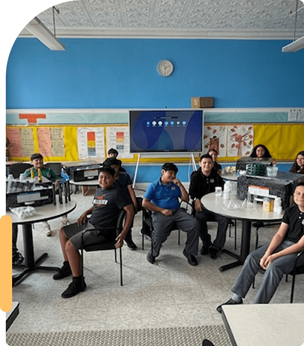 Students wearing masks in a classroom setting, seated and engaged.